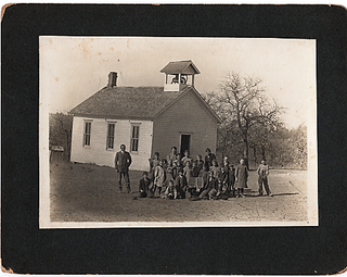 ORIGINAL PHOTOGRAPH OF STUDENTS AND THEIR MALE TEACHER, OUTSIDE A ONE-ROOM SCHOOLHOUSE WITH BELFRY