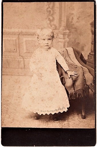 Item #040473 BLUFFTON, OHIO PHOTOGRAPHER'S 1887 CABINET CARD OF A VERY YOUNG GIRL IN VICTORIAN LACE DRESS, LEFT HAND RESTING ON AN AFGHAN-COVERED CHAIR. Bluffton / Triplett Ohio, Will A.