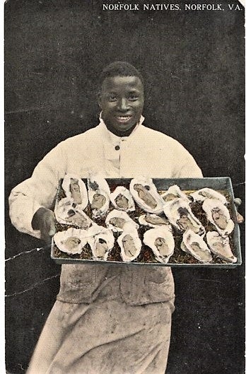 Item #041335 "NORFOLK NATIVES": TINTED, REAL-PHOTO POSTCARD OF AN AFRICAN-AMERICAN CHEF DISPLAYING A LARGE TRAY OF OYSTERS ON THE HALF-SHELL. Norfolk Virginia.